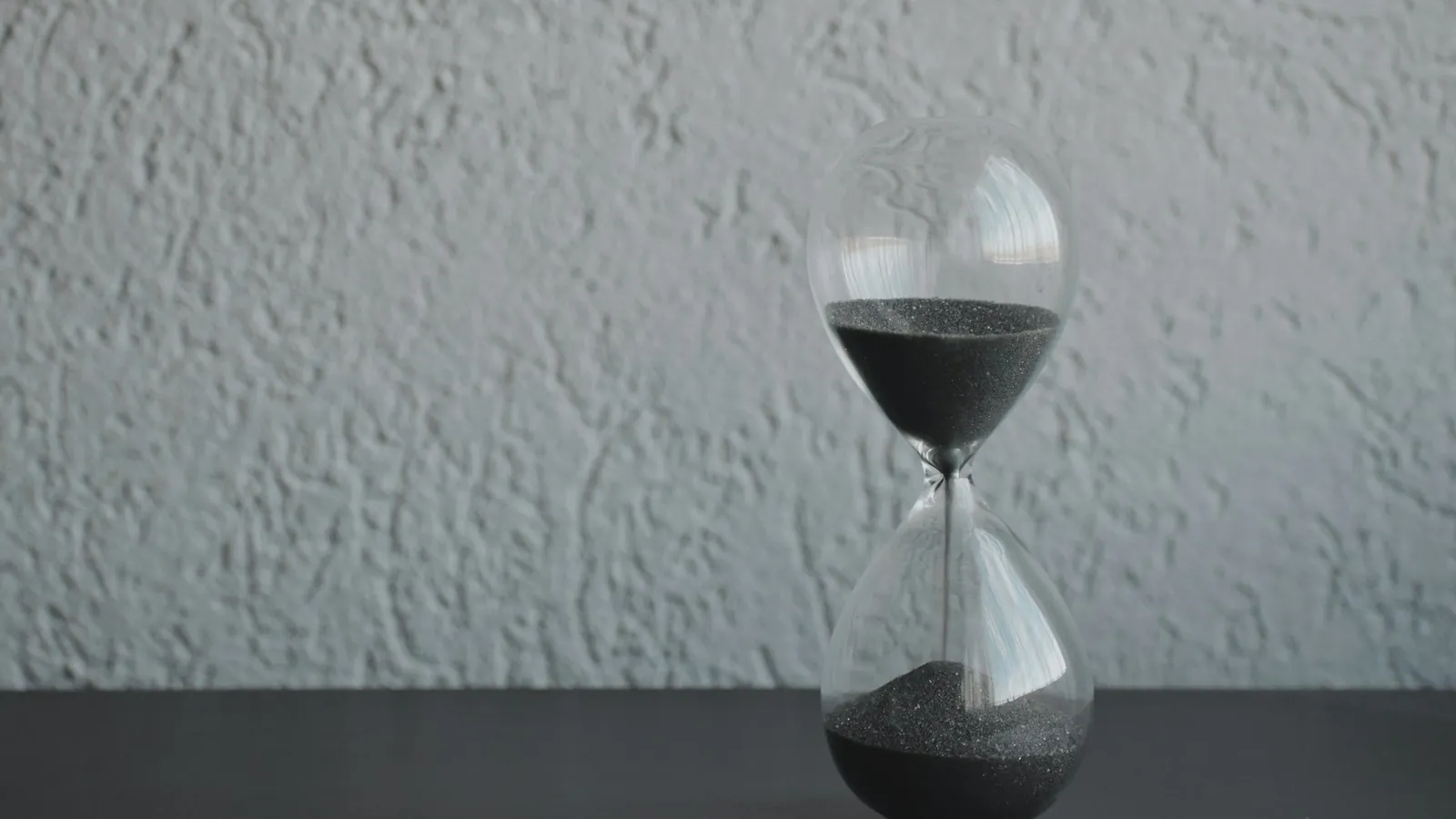 Sanduhr vor einer grauen Wand